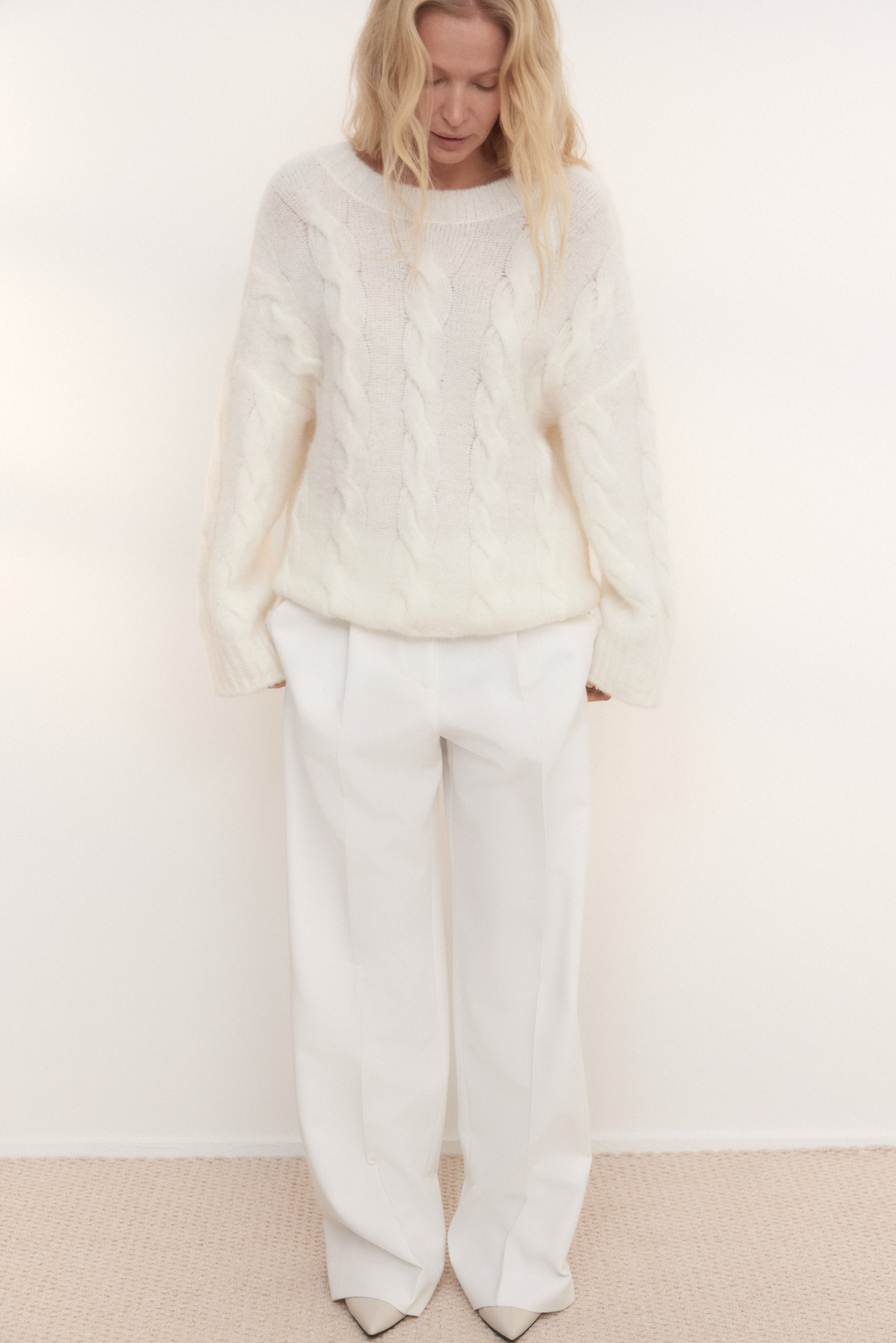 Трикотажный джемпер из шерсти и мохера. Модель свободного силуэта со спущенной линией плеч, длинными рукавами, круглой горловиной и глубоким вырезом на спине, фиксирующимся шнурком. Изделие декорировано фактурной вязкой в виде кос. Края изделия выполнены в рубчик.