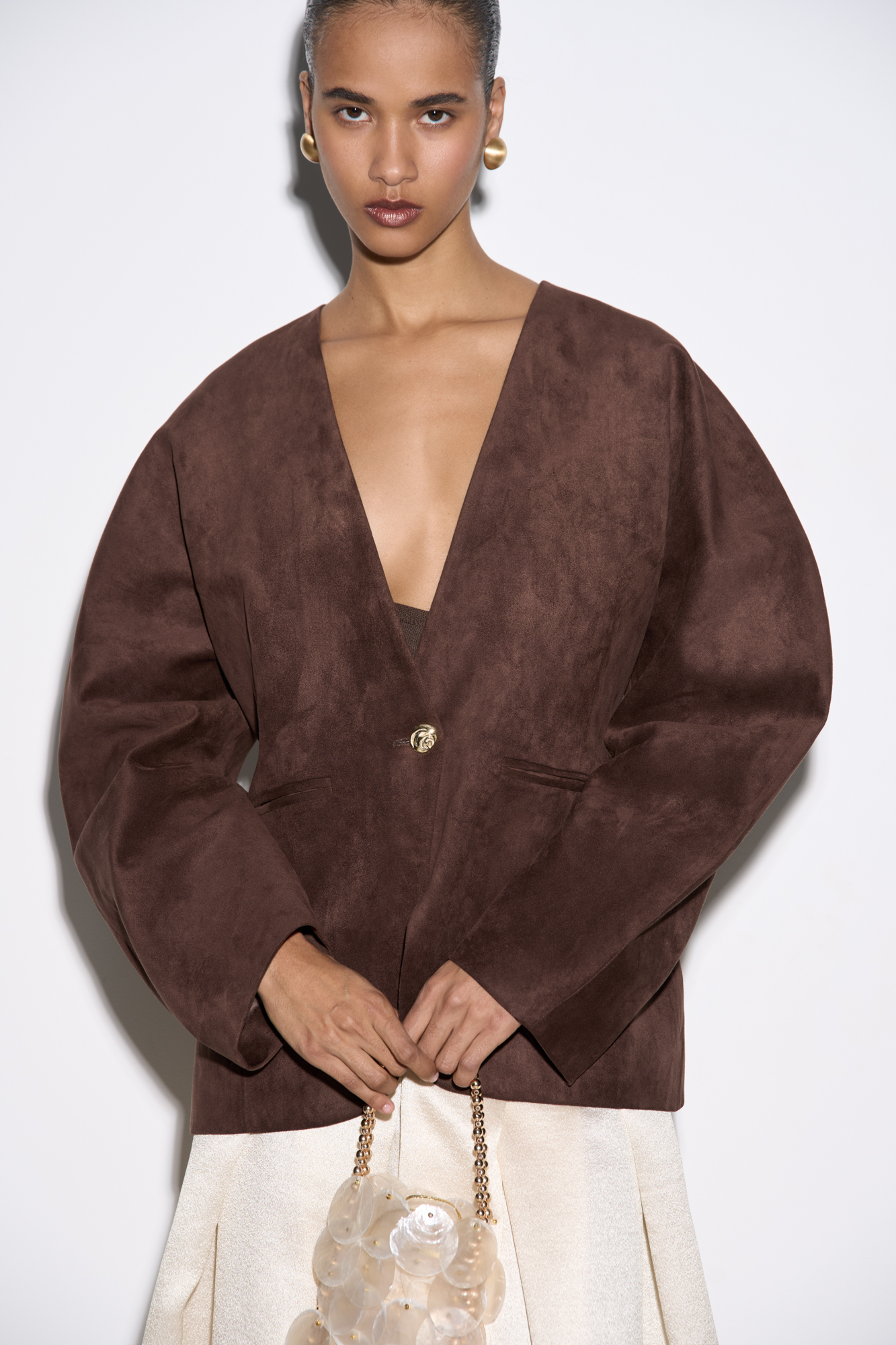 Однобортный жакет из ткани с имитацией внешнего вида и свойств натуральной замши. Модель без лацканов с большими объемными рукавами и боковыми прорезными карманами. Изделие на подкладке.