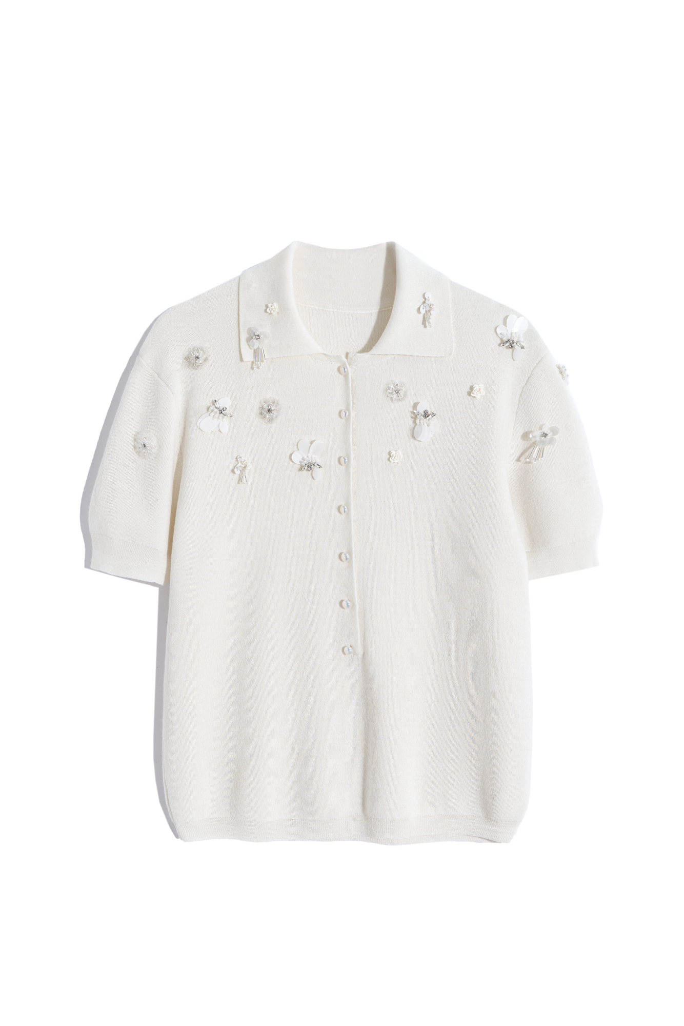 Трикотажная футболка поло из шерсти. Модель свободного силуэта с воротником поло и низкой планкой на пуговицах. Изделие декорировано цветами из бисера и пайеток.
