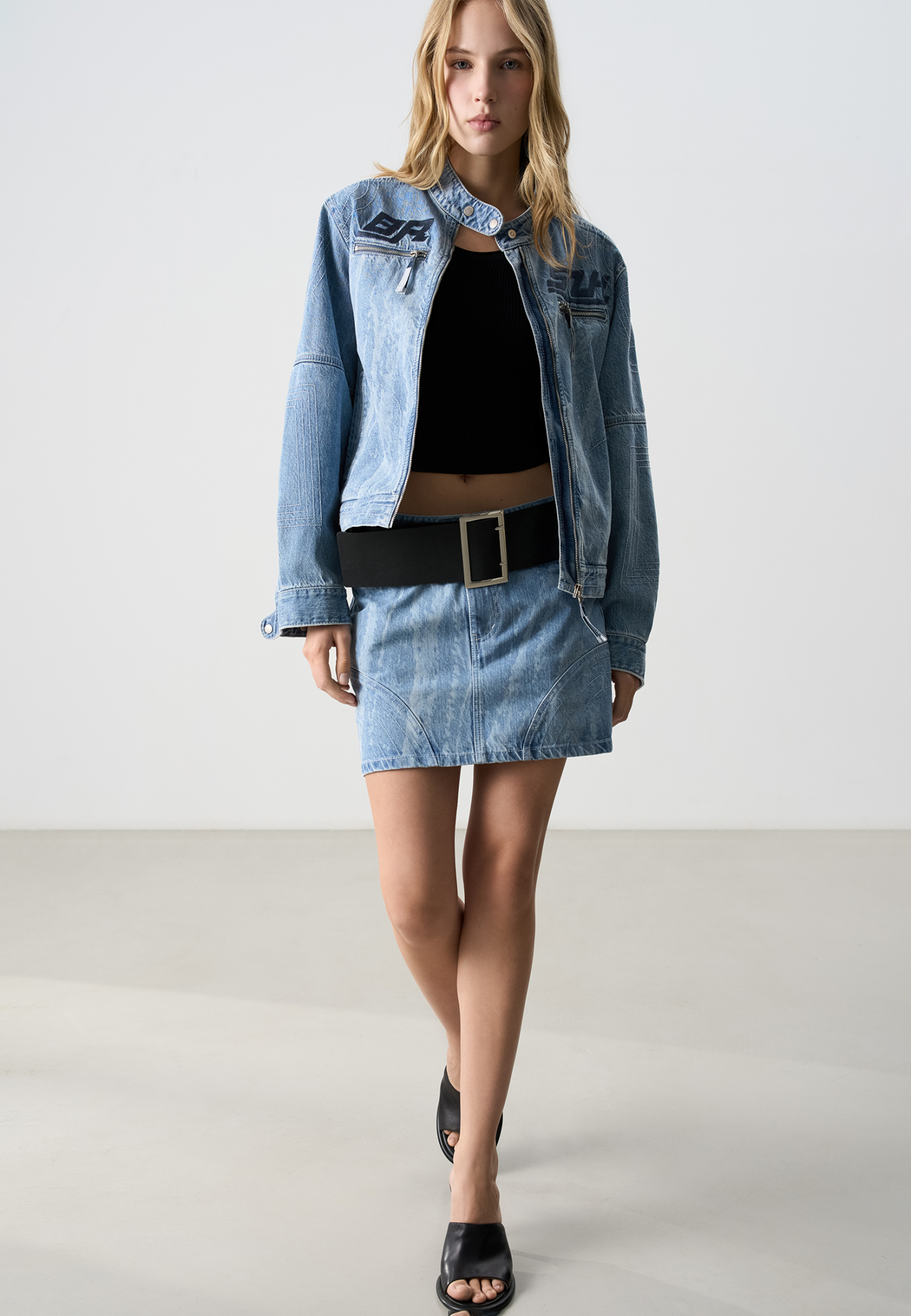 Джинсовая юбка длины мини. Изделие декорировано отстрочкой контрастного цвета, формирующей графические акценты. Застежка на молнию и пуговицу. Без подкладки. 