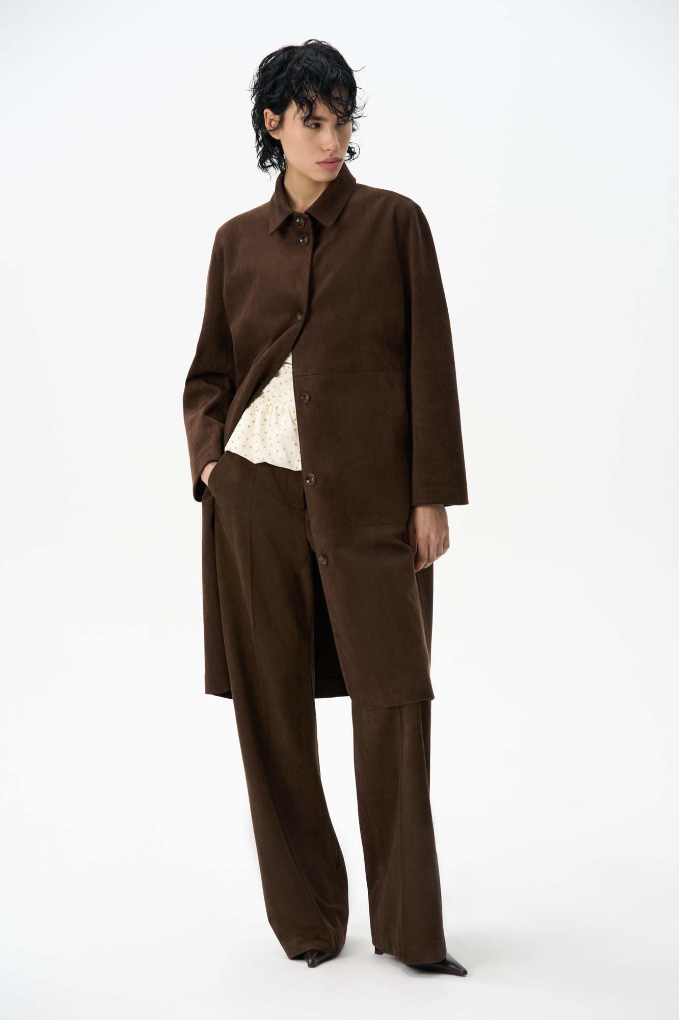 Тренч из ткани с имитацией внешнего вида и свойств натуральной замши. Модель прямого кроя с отложным воротником. Застежка на крупные пуговицы.