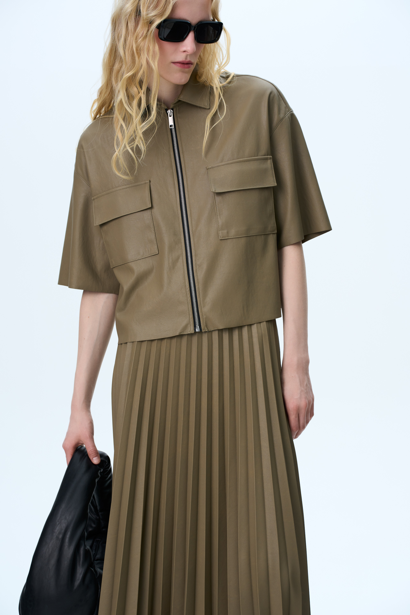 Укороченная рубашка из экокожи. Модель свободного силуэта со спущенной линией плеча, накладными карманами на груди и застежкой на молнию.