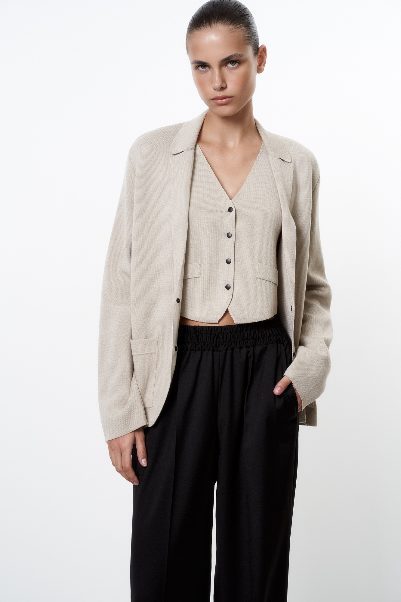 Трикотажный однобортный жакет из шерсти мериноса. Модель свободного силуэта, с узкими лацканами и двумя накладными карманами. Застежка на две кнопки. Дополнить образ можно жилетом, юбкой или брюками.