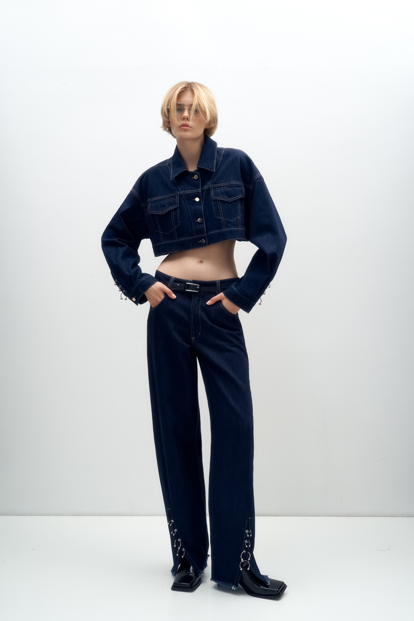 Джинсы из 100% хлопка. Модель прямого силуэта с разрезами спереди, декорированными металлической фурнитурой в виде пирсинга. Пять карманов, паты на поясе для ремня, застежка на молнию и пуговицу. Дополнить образ можно джинсовкой в таком же стиле.