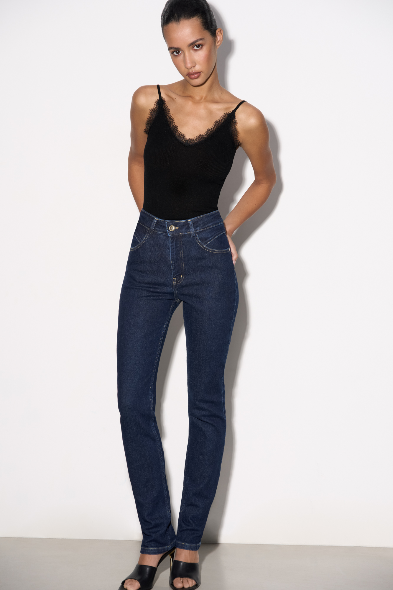 Джинсы слим фит с высокой посадкой. Модель по фигуре с декоративной отстрочкой на поясе. Четыре кармана, застежка на молнию и металлическую пуговицу.