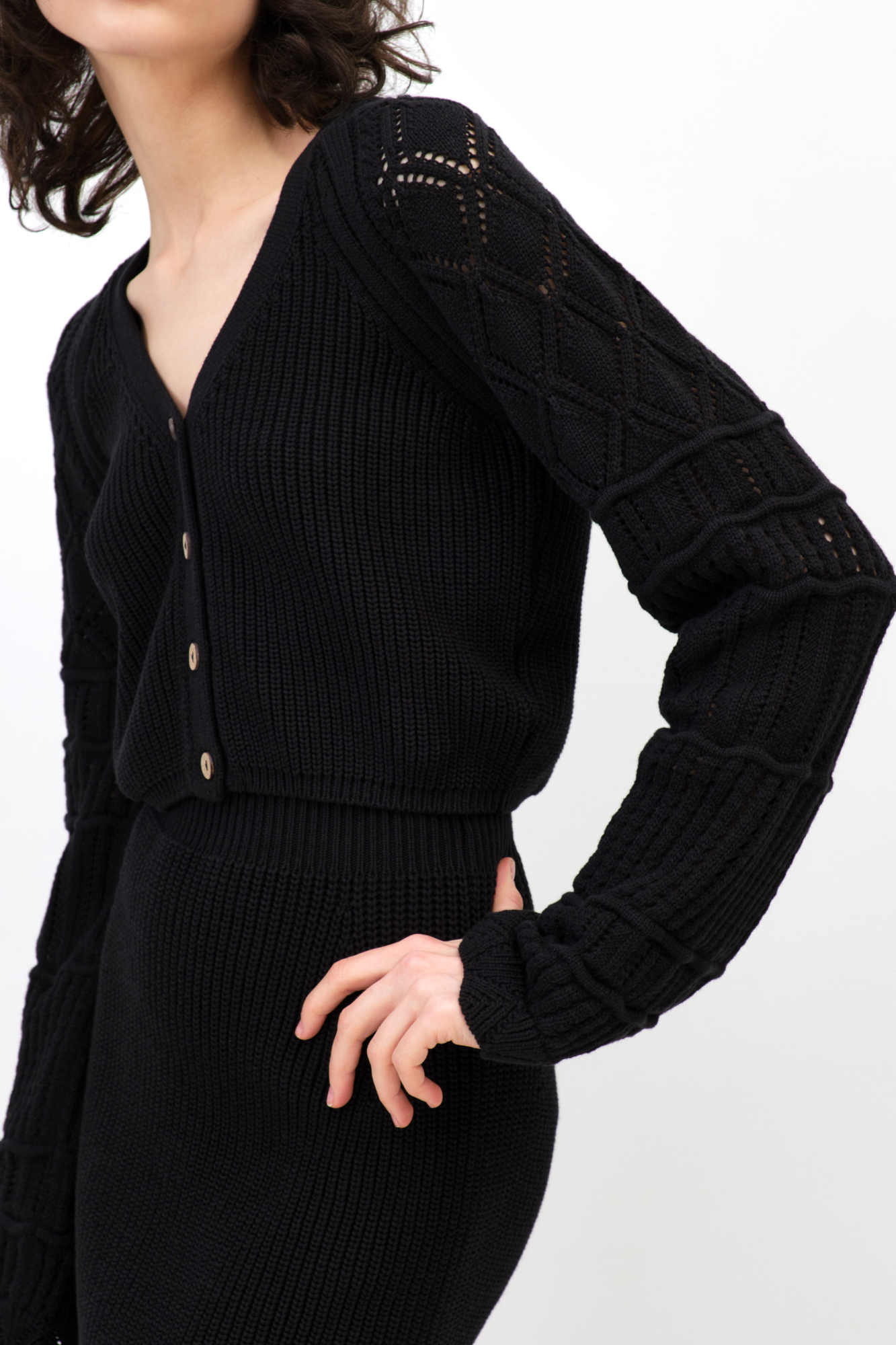 Трикотажный кардиган из хлопка с добавлением эластана. Модель укороченного кроя, с длинными вывязанными рукавами и застежкой на пуговицы.