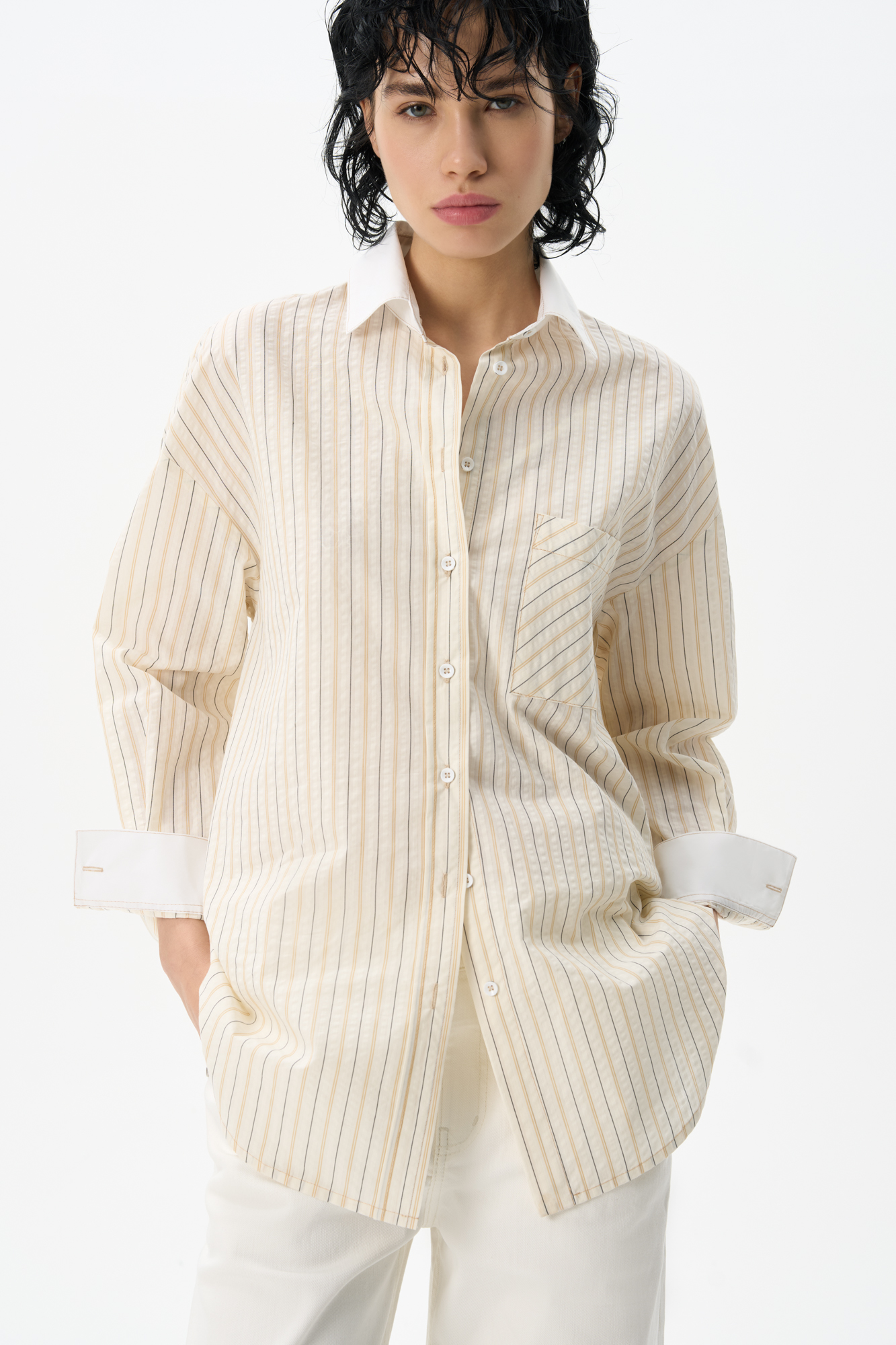 Рубашка, выполненная из 100% хлопка, с принтом в полоску с отнотонными манжетами и отложным воротником. Модель прямого кроя со спущенной линией плеч. Рубашка с двумя вариантами застежки: классическим и наискосок. 