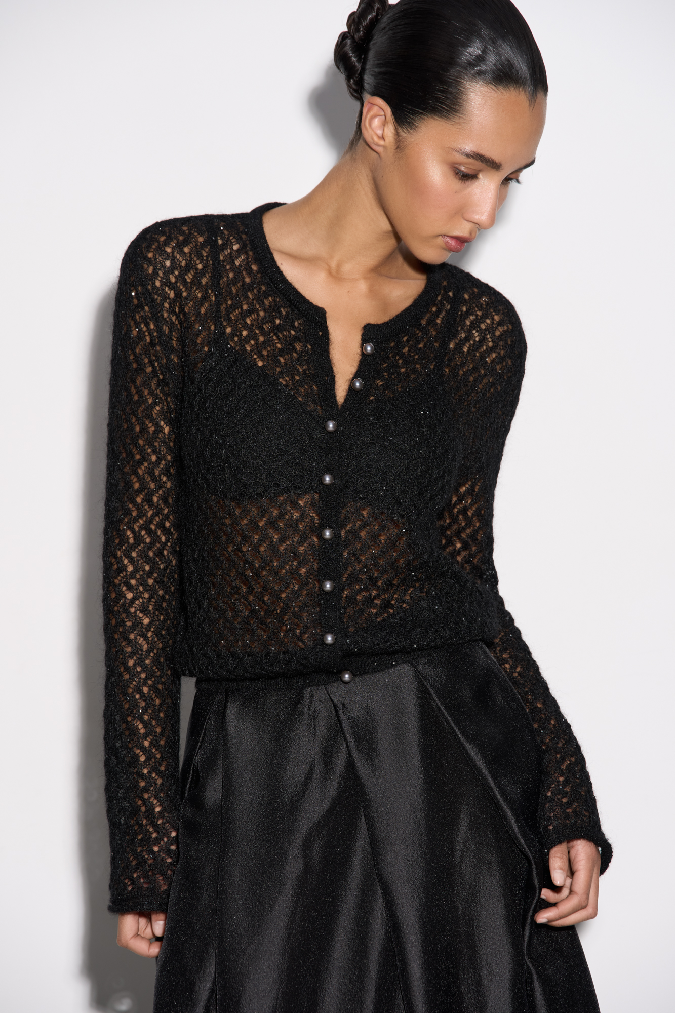 Трикотажный ажурный кардиган из кидмохера, декорированный мелкими пайетками. Модель свободного силуэта с длинными рукавами, круглым вырезом горловины и застежкой на жемчужные пуговицы. 