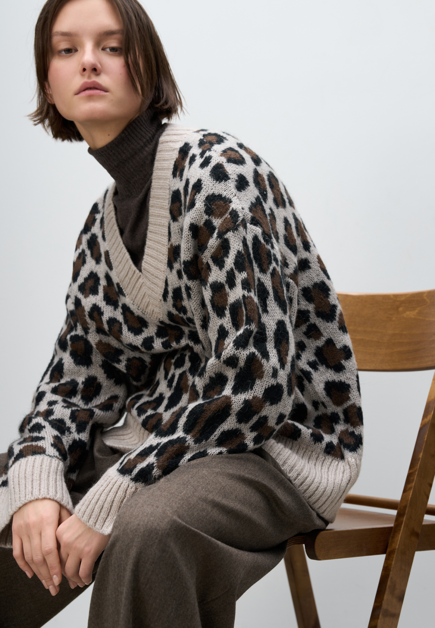 Трикотажный джемпер с жаккардовым анималистическим рисунком. Модель свободного силуэта со спущенной линией плеча и V-образным вырезом горловины. Края изделия выполнены в рубчик.