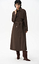 Двубортный длинный тренч прямого кроя. Модель с отложным воротником, декорированным металлической перемычкой, отлетной кокеткой, патами с пуговицами на манжетах, карманами и шлевками на талии для пояса.