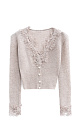 Короткий трикотажный кардиган из тонкой шерсти мериноса экстрафайн и альпака экстрафайн. Модель по фигуре с глубоким V-образным вырезом. Застежка на маленькие жемчужные пуговицы. Изделие декорировано тонким кружевом.