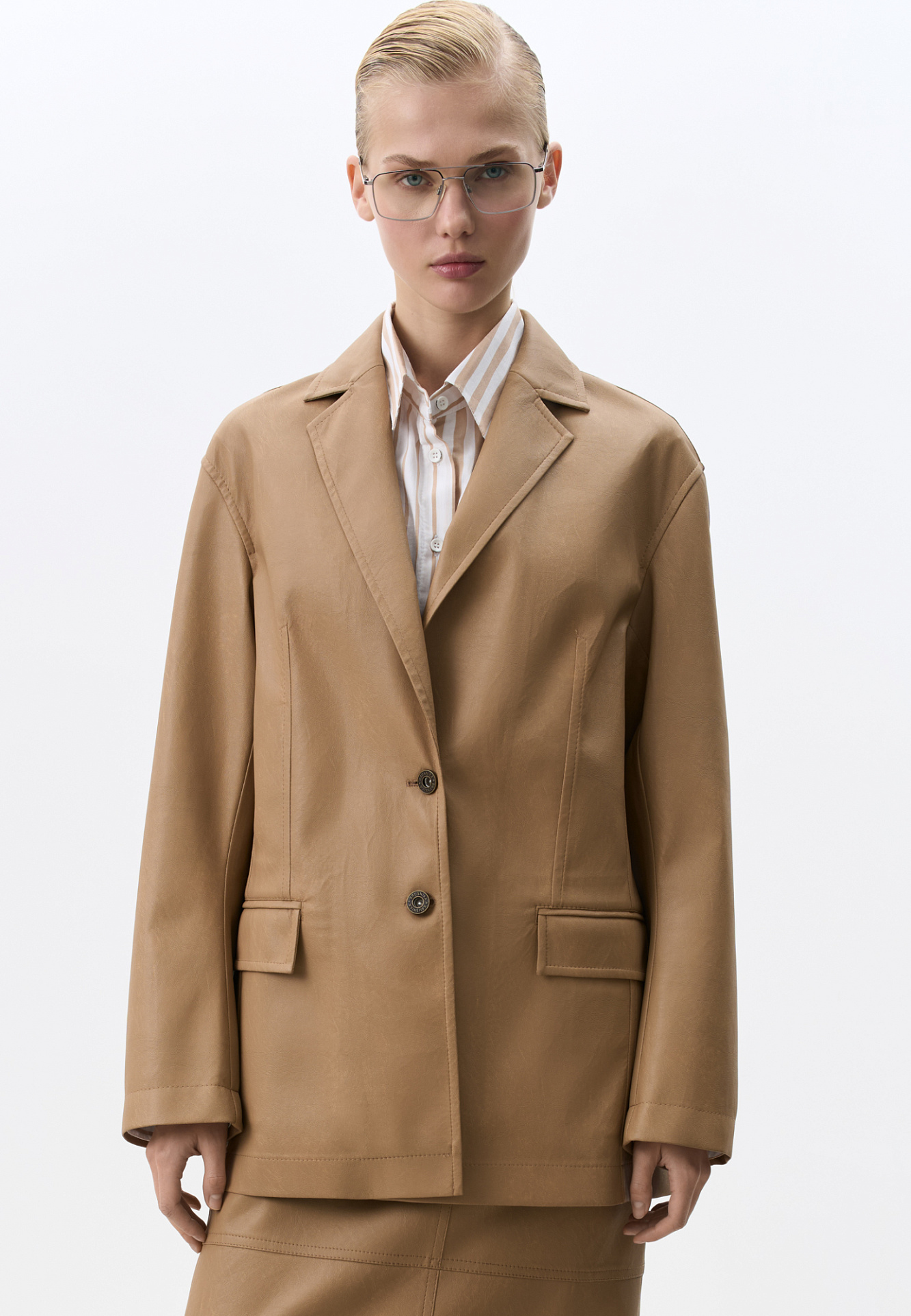 Однобортный жакет прямого кроя из пластичной двусторонней экокожи. Передние карманы с клапанами. Застежка на пуговицы.