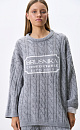 Трикотажный джемпер с объемными косами из мягкой шерсти. Модель свободного силуэта, со спущенной линией плеч и круглым вырезом. Изделие декорировано брендированным жаккардом на груди. Дополнить образ можно брюками и юбкой в том же стиле.