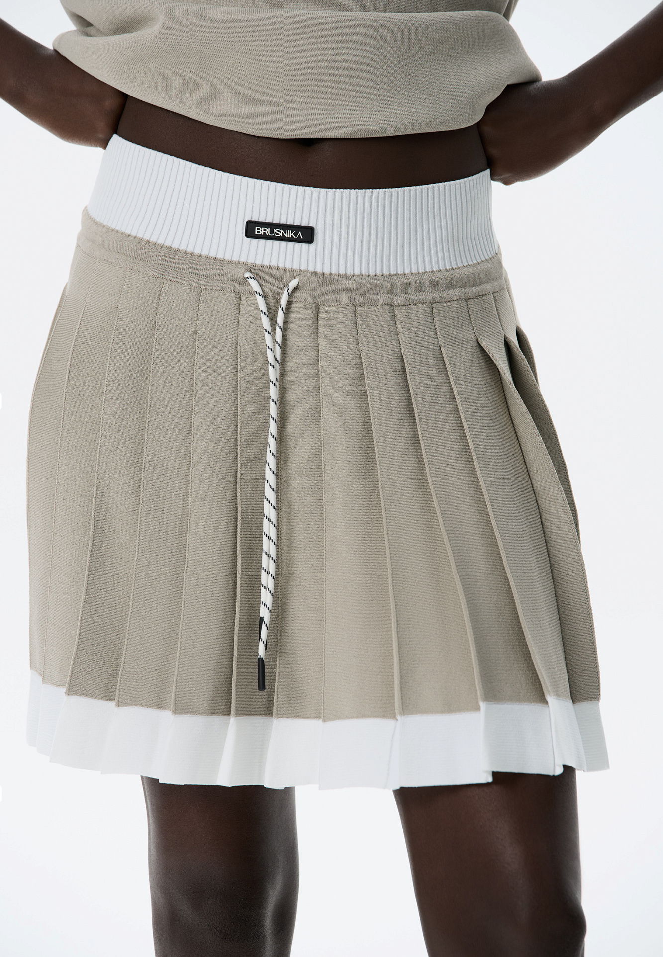 Трикотажная юбка плиссе длины мини из вискозы. Модель с широким эластичным поясом в рубчик. Пояс и нижняя часть юбки выполнены из пряжи контрастного цвета.