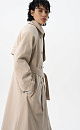 Двубортный длинный тренч прямого кроя. Модель с отложным воротником, декорированным металлической перемычкой, отлетной кокеткой, патами с пуговицами на манжетах, карманами и шлевками на талии для пояса.