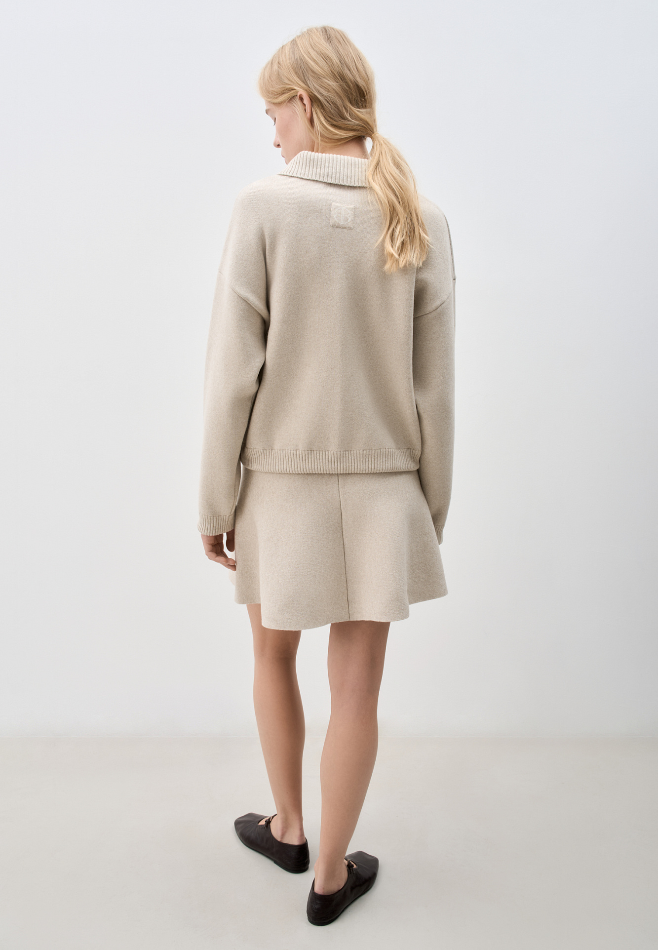 Трикотажная юбка длины мини из кашемира и шерсти. Модель полусолнце, с эластичным поясом на резинке, тонкими лампасами контрастного цвета и брендированным жаккардом. Дополнить образ можно бомбером в таком же стиле.