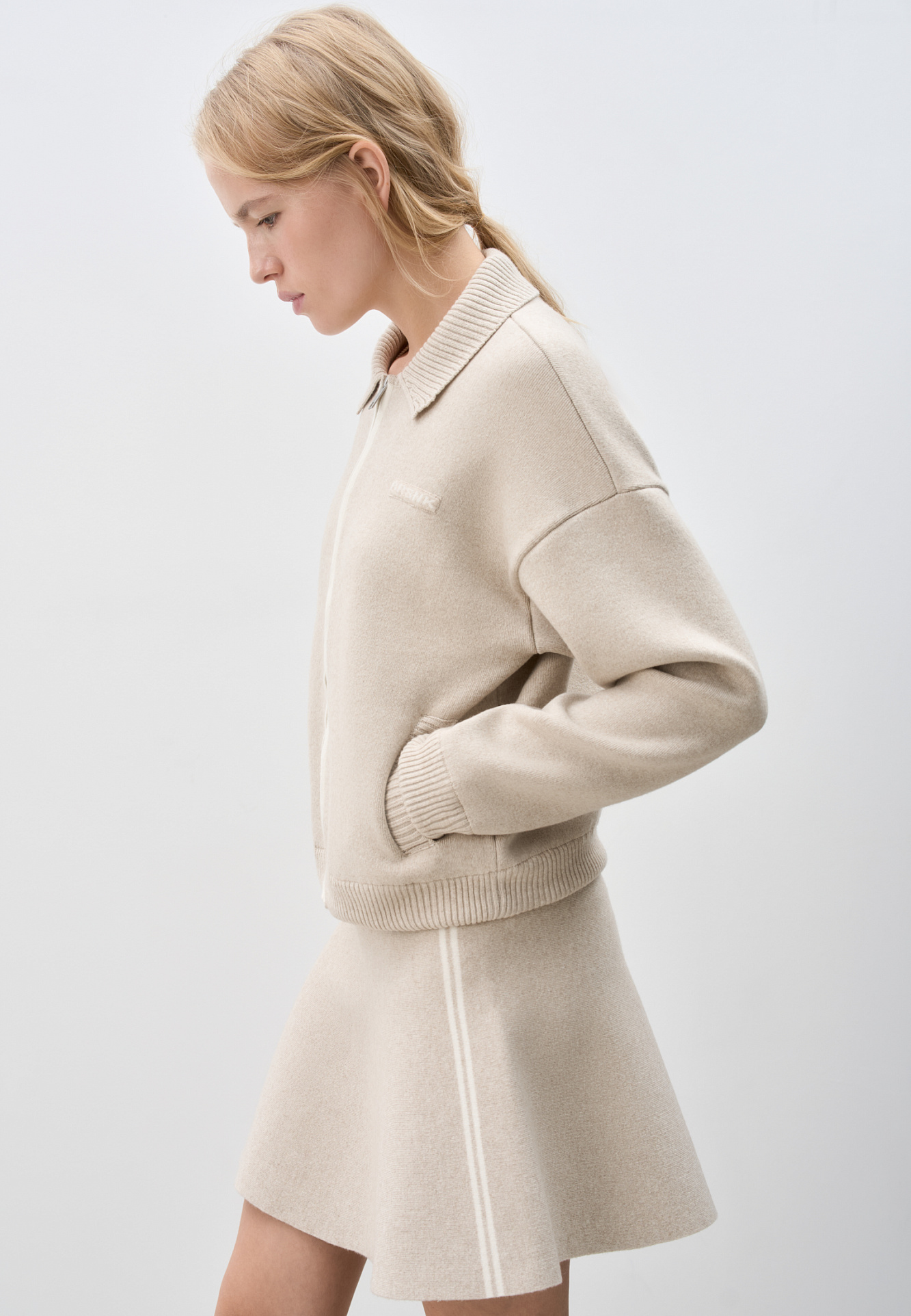 Трикотажная юбка длины мини из кашемира и шерсти. Модель полусолнце, с эластичным поясом на резинке, тонкими лампасами контрастного цвета и брендированным жаккардом. Дополнить образ можно бомбером в таком же стиле.