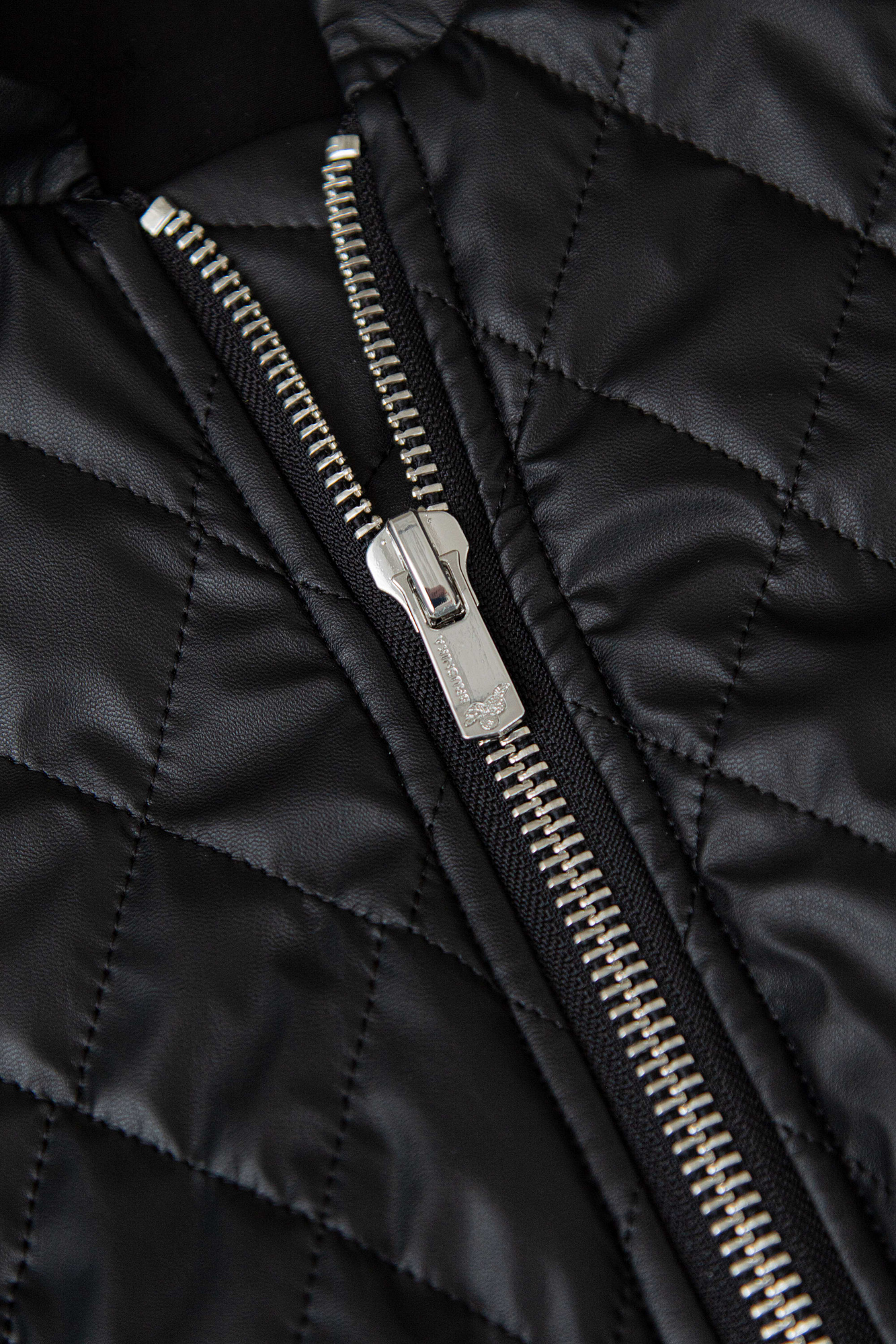 Укороченный стеганый бомбер из экокожи с воротником стойкой. Длинные рукава с манжетами на кнопках. Передние боковые карманы. Эластичный широкий пояс на резинке. Застегивается на металлическую молнию.