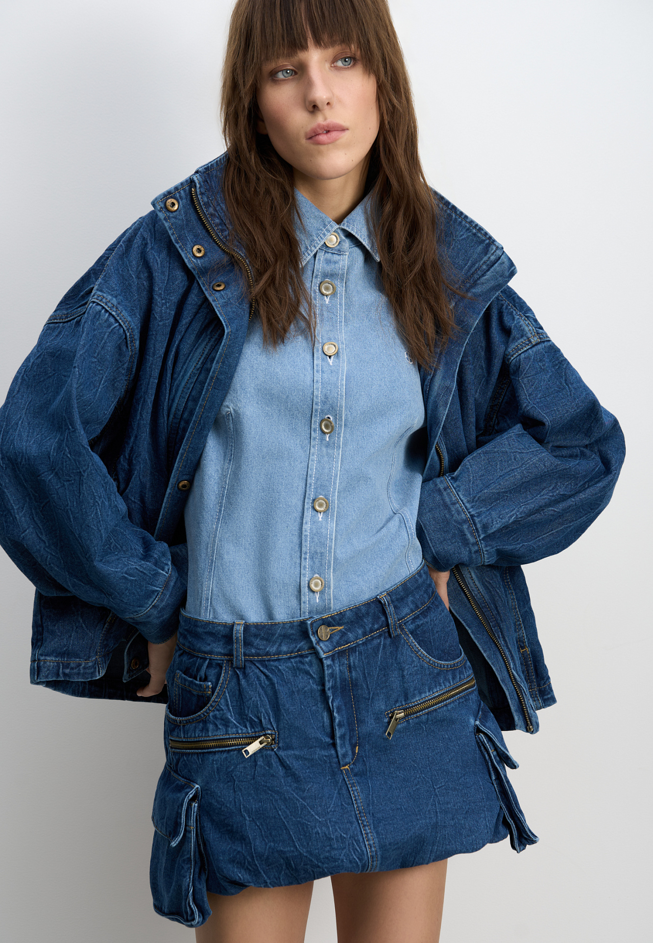 Джинсовая мини-юбка баллон из 100% хлопка. Модель с большими накладными карманами с клапанами по бокам, врезными карманами, шлевками на поясе для ремня и застежкой на молнию и пуговицу.