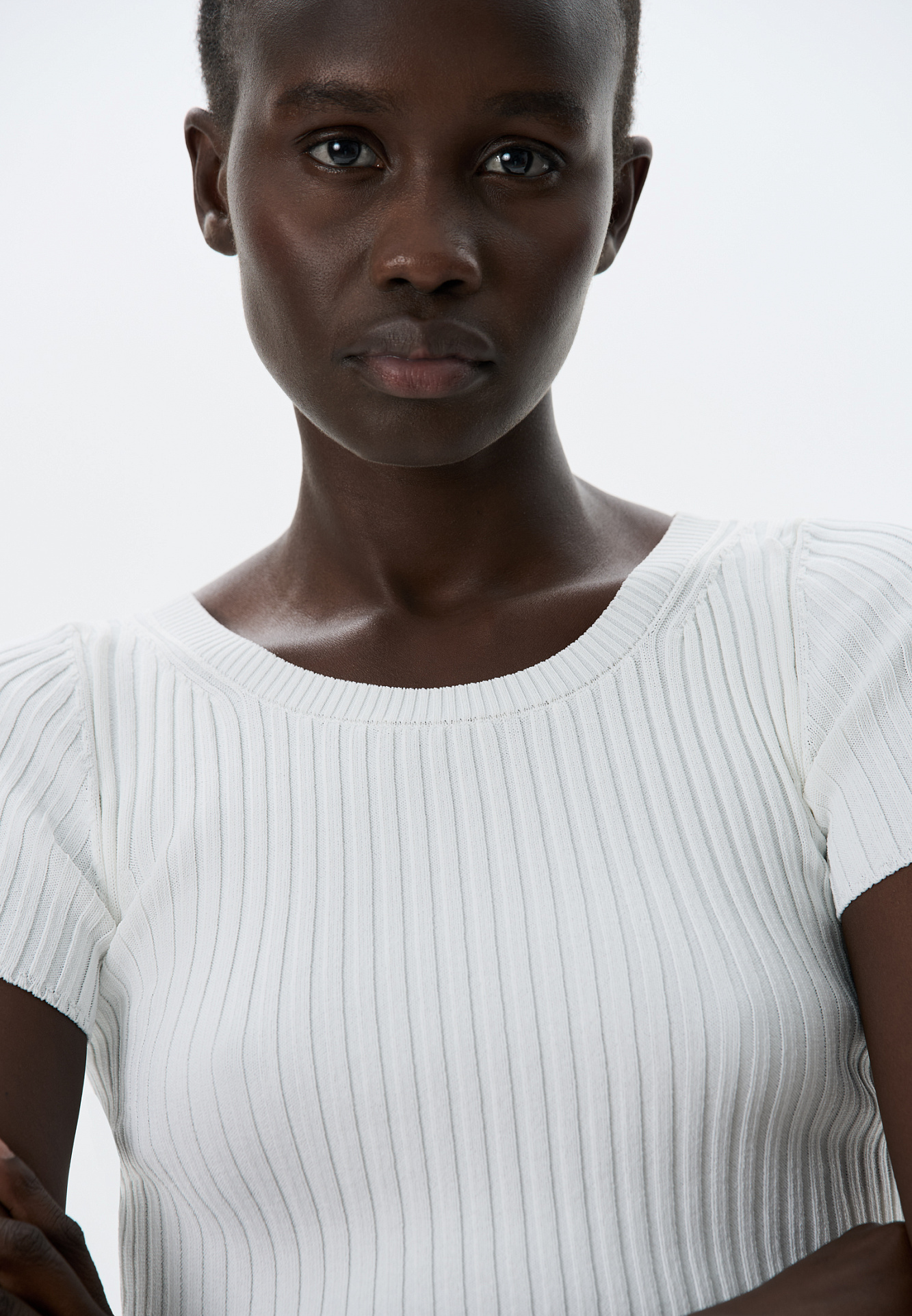 Короткий трикотажный топ из вискозы в рубчик. Модель приталенного силуэта с короткими рукавами и круглым вырезом горловины. Дополнить образ можно юбкой плиссе.