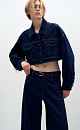 Укороченная куртка прямого кроя из денима с отложным воротником и хлястиками на поясе. Модель декорирована накладными карманами на груди, металлической фурнитурой в виде пирсинга на манжетах и брендированным ярлыком на спине. Застежка на пуговицы.