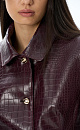 Однобортный жакет из фактурной экокожи. Модель приталенного силуэта с вытачками по фигуре, отложным воротником, подплечниками, длинными рукавами и карманами с клапанами. Застежка на кнопки. Дополнить образ можно комплектной юбкой.