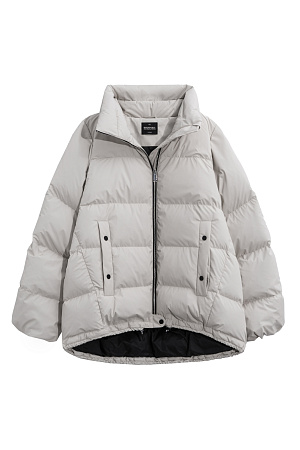 бежевый Объемный стеганый пуховик. Модель свободного силуэта с боковыми карманами на кнопках, воротником-стойкой и капюшоном. Низ изделия выполнен на регулируемой кулиске. Застежка на молнию и кнопку.