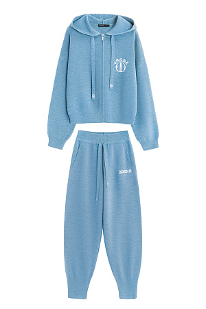 голубой Трикотажный костюм в спортивном стиле из шерсти с добавлением акрила, состоящий из бомбера и брюк. Бомбер свободного силуэта, со спущенной линией плеча и капюшоном на кулиске. Низ изделия и манжеты рукавов выполнены на эластичной резинке. Застежка на молнию. <br />
Брюки с широким эластичным поясом на кулиске, боковыми карманами и широкими манжетами на резинке. Изделие декорировано брендированным жаккардом.