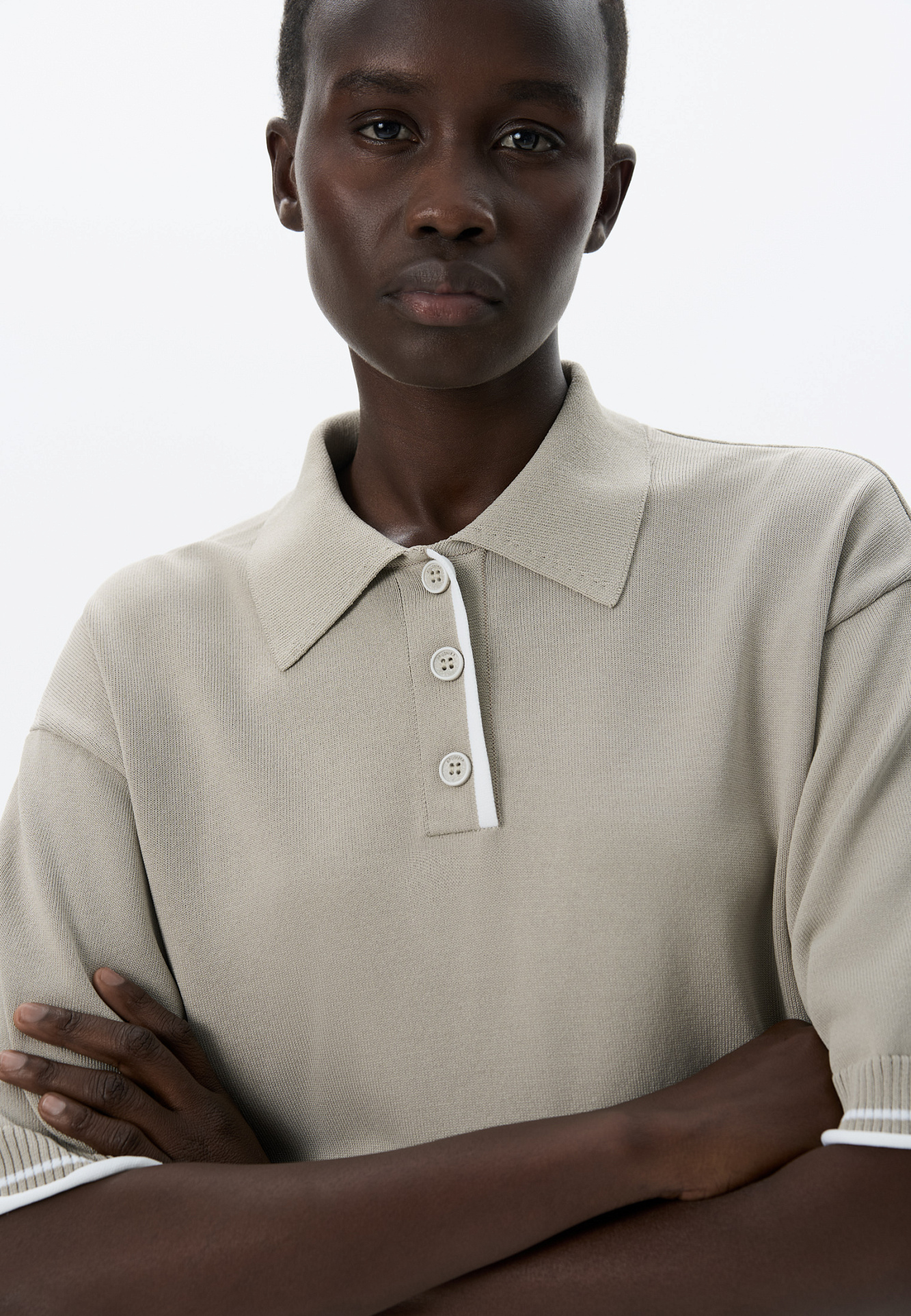 Трикотажная футболка поло из вискозы. Модель прямого силуэта, со спущенной линией плеч, короткими рукавами, отложным воротником-поло и планкой с тремя пуговицами. Рукава и нижний край изделия декорированы кантом контрастного цвета.