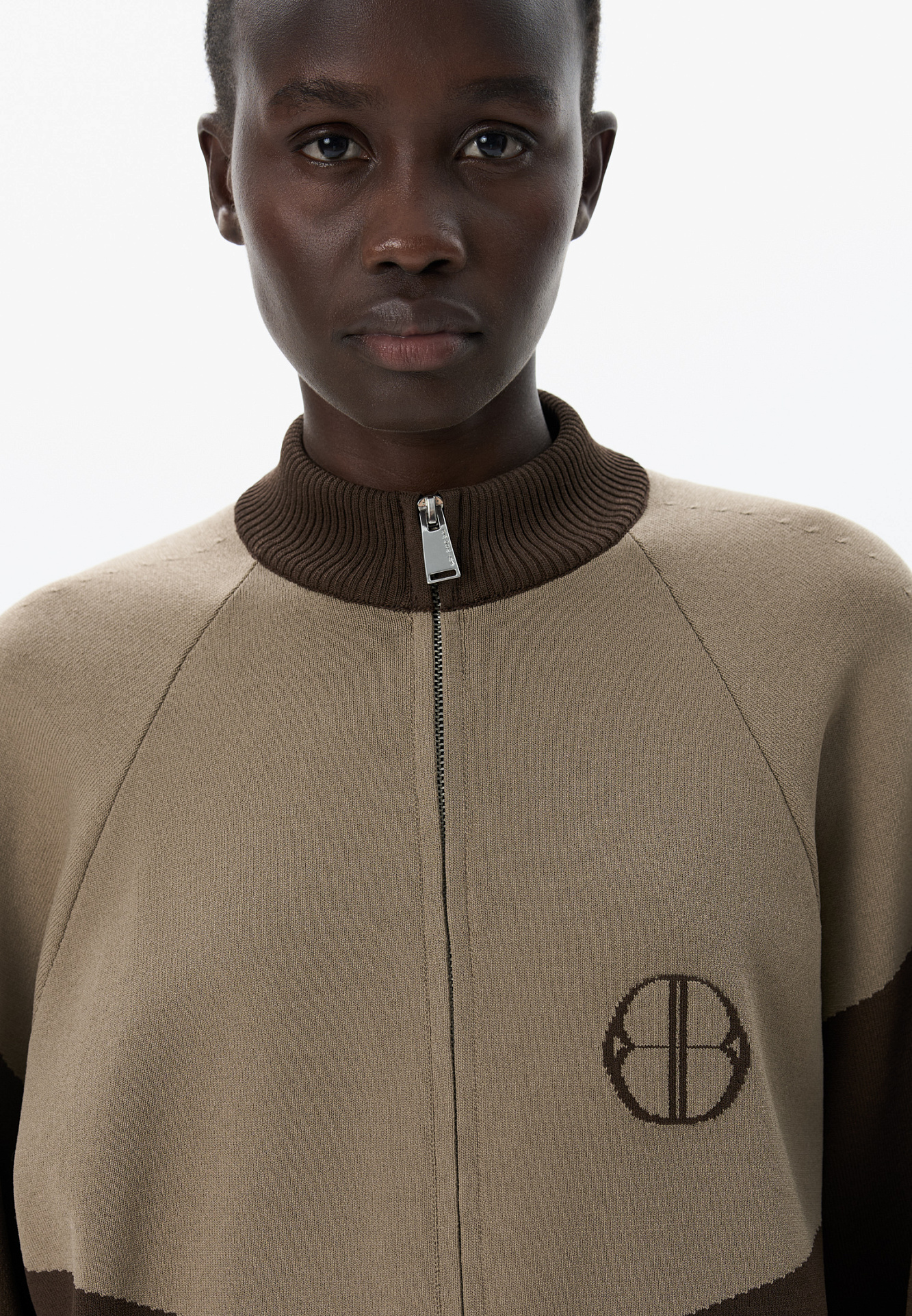 Трикотажный бомбер из вискозы с добавлением эластана. Модель прямого силуэта, с рукавом реглан, невысоким воротником-стойкой и боковыми карманами. Изделие декорировано брендированным жаккардом на груди. Застежка на молнию.