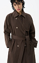 Двубортный длинный тренч прямого кроя. Модель с отложным воротником, декорированным металлической перемычкой, отлетной кокеткой, патами с пуговицами на манжетах, карманами и шлевками на талии для пояса.