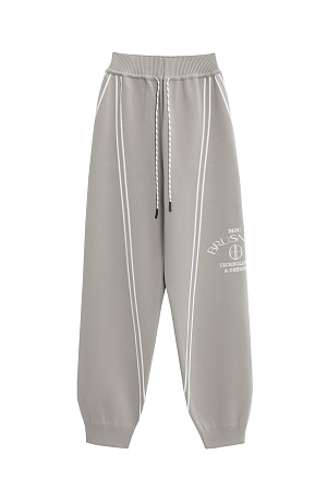 бежевый Трикотажные джоггеры из вискозы. Модель свободного силуэта, с широким эластичным поясом на кулиске, боковыми и задними карманами. Изделие декорировано брендированным жаккардом и лампасами контрастного цвета.