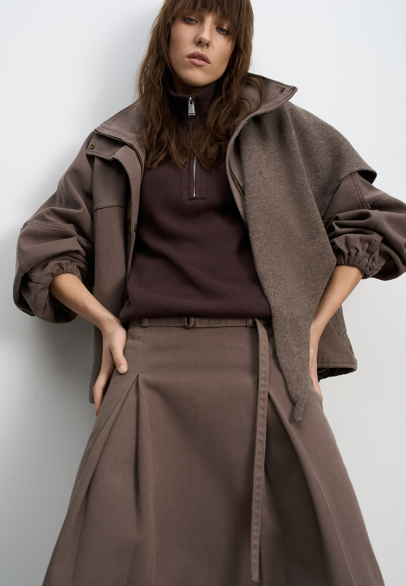 Джинсовая юбка из 100% хлопка длины миди. Модель прямого кроя, с крупными встречными складками, двойным поясом со шлевками для ремня, тонким ремешком и застежкой на молнию сбоку.