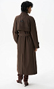 Двубортный длинный тренч прямого кроя. Модель с отложным воротником, декорированным металлической перемычкой, отлетной кокеткой, патами с пуговицами на манжетах, карманами и шлевками на талии для пояса.