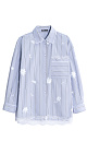 Рубашка в полоску из 100% хлопка. Модель свободного силуэта с длинными рукавами, отложным воротником и накладным карманом на груди. Изделие декорировано кружевом и вышивкой из пайеток.