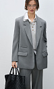 Классический жакет с накладными карманами, подплечниками, разрезами по бокам и удлиненной спинкой. Длинные рукава на манжетах без пуговиц. Застежка на пуговицу.